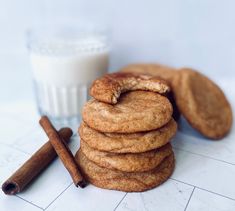 cinnamon cookies stacked on top of each other next to a glass of milk and cinnamon sticks