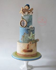 a three tiered cake decorated with an airplane, compass and monkey figurine