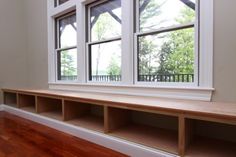 an empty room with three windows and wooden flooring in front of the window sill