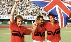 two men holding up a british flag in front of a large stadium full of people