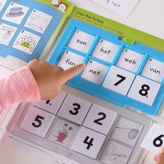 a child's hand is pointing at the numbers on an activity book with matching cards