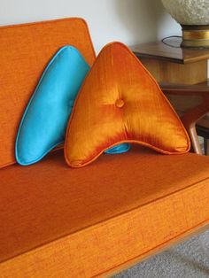 an orange couch with two blue pillows on it