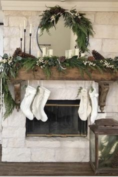 a fireplace decorated for christmas with stockings and greenery