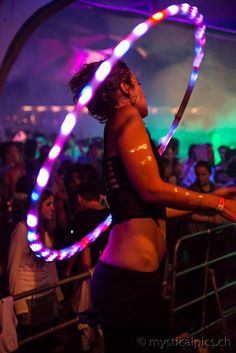 a woman holding a hula hoop in front of a crowd