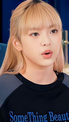 a young woman with blonde hair and bangs wearing a black t - shirt that says something beautiful