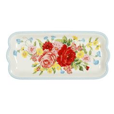 a white plate with red and yellow flowers on the front, blue trim around the edge