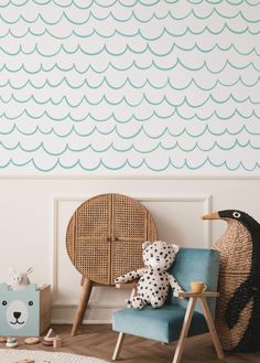 a blue chair sitting in front of a wall with waves painted on it and a stuffed animal next to it