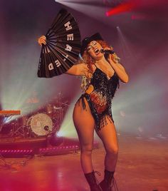 a woman in a costume holding a fan on stage