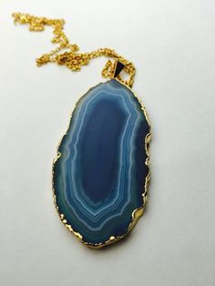 "This listing includes a Blue Agate Necklace on a gold plated stainless steel chain. Each stone is unique and will not look exactly like the picture as each stone is natural and raw. It is rimmed in 24k Gold plating and will hang on a gold plated stainless steel chain in your choice of length. The average length is 30\". Please know that this is not the exact piece you will get. These are natural and each is unique in size, shape and color!! Each one measures approximately 50-74mm long. *Stainle Gold Agate Jewelry With Adjustable Chain, Gold Agate Round Pendant Crystal Necklace, Gold Agate Pendant Crystal Necklace, Gold Agate Crystal Necklace With Round Pendant, Gold Agate Crystal Necklace For Spiritual Wear, Gold Agate Spiritual Crystal Necklace, Gold Agate Crystal Necklace For Gifts, Gold Agate Necklace With Large Stone, Spiritual Gold Agate Necklace