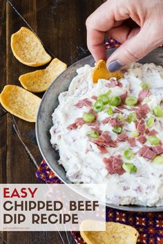 a person is dipping some chips into a bowl of dip with bacon and green onions