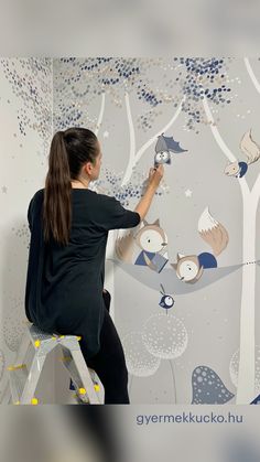 a woman is painting a mural on the wall