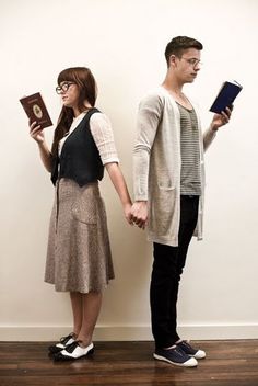 two people standing next to each other holding books