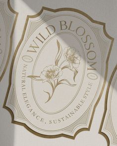 the logo for wild blossom is shown in white and gold foil on a gray background