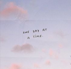 the words one day at a time written in black ink on a pink and blue sky