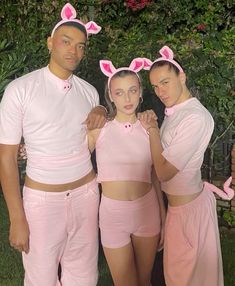 three people in bunny ears and pink outfits posing for the camera with their arms around each other