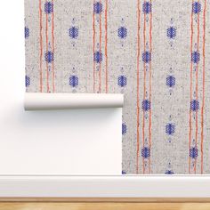 a white wall with blue and orange designs on it next to a roll of paper