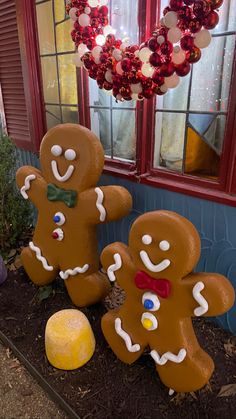 two gingerbread men standing next to each other in front of a window