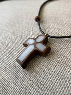 a wooden cross is sitting on the ground with a brown cord around it and white glass in the center