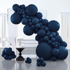 blue balloons floating in the air next to a table with an hourglass on it