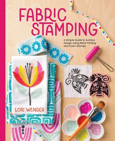 the book cover for fabric stamping is displayed on a wooden table with craft supplies