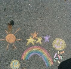 someone is standing on the sidewalk with chalk drawings and crayons