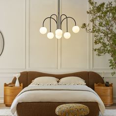 a bedroom with a bed, ottoman and plant in the corner on the wall next to it