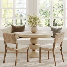 a dining room table with chairs and a vase filled with flowers on top of it