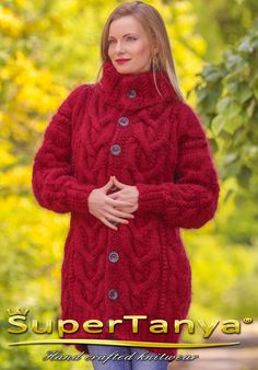 a woman wearing a red sweater and jeans standing in front of trees with her hands on her hips