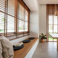 a living room filled with lots of furniture next to windows covered in wooden slats