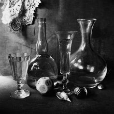 black and white photograph of three vases, one with a wine glass on the table