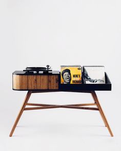 a record player on a wooden table with vinyl records and magazines sitting on it's side