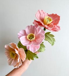 three paper flowers are being held by a person's hand