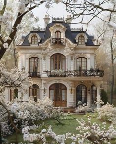 a large white house surrounded by trees and flowers