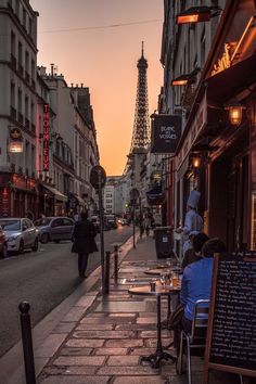 people are sitting at tables on the sidewalk near the eiffel tower in paris