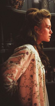 a woman standing in front of a shelf filled with vases and other things on it