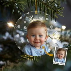 a baby's first christmas ornament hanging from a tree with snowflakes