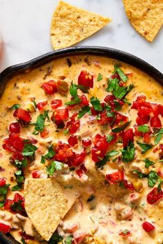 tortilla dip in a cast iron skillet topped with tomatoes, cheese and cilantro