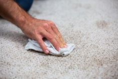 a person wiping up the carpet with a cloth on it's end and hand