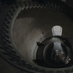 people are walking up and down the stairs in a spiral stair case at night time