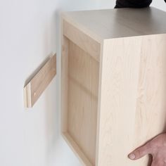 a person is standing on top of a wooden shelf with their hand on the edge