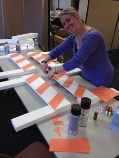 a woman sitting at a table with some orange and white strips on the top of it