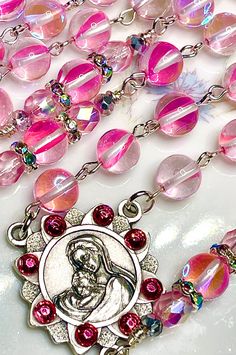 So ethereal, this beautiful fairytale pink rosary is made completely of smooth round mystic aura Quartz gemstones with aurora borealis Preciosa crystals, and they have a gorgeous blue rainbow that reflects in the light. This gemstone has a very nice density, so this rosary is perfect if you like your rosary to have some weight to it. All of the prayers are said on the 8mm faceted gemstones, and the Pater prayers are flanked with embellishments and pink Preciosa crystal beads. I have crystallized Pink 8mm Beads Jewelry For Wedding, Pink Rosary With Round Beads For First Communion, Pink Rosary For First Communion, Pink Spiritual Jewelry For First Communion, Pink Rosary, Catholic Communion, Mystic Quartz, Quartz Gemstones, Bouquet Bridal