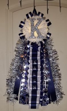 a blue and white christmas tree with silver tinsel on it's top, hanging from hooks