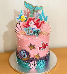 a pink and blue cake decorated with little mermaids