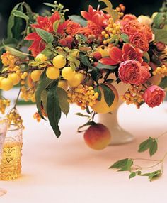 an arrangement of fruit and flowers on a table