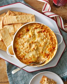 a casserole dish with cheese and crackers on the side