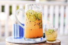 a pitcher filled with lemonade and lime slices next to two glasses on a table