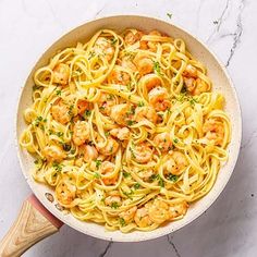 pasta with shrimp and parsley in a skillet on a marble countertop, viewed from above