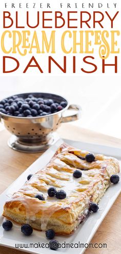 blueberry cream cheese danish on a white plate next to a bowl of blackberries