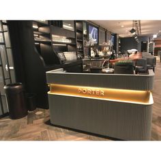 the front desk of a bar with gold lettering on it and black chairs in the background